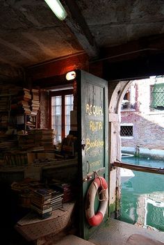 an open door leading into a room with books on the floor and a boat in the water