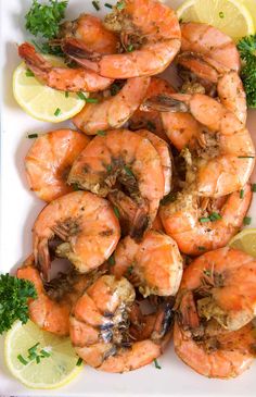 cooked shrimp with lemon wedges and parsley garnish on a white platter