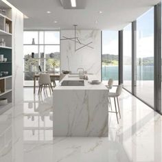 a large kitchen with marble counter tops and white walls, along with floor to ceiling windows