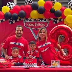 a group of people standing next to each other in front of a table with balloons