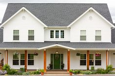 a large white house with lots of windows and plants on the front porch, along with an entry way