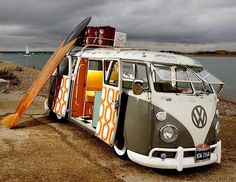 an old vw bus is parked on the beach with surfboards sticking out of it