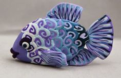 a purple and blue fish figurine sitting on top of a white countertop