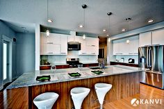 a kitchen with white cabinets and marble counter tops