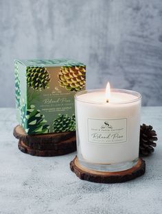 a white candle sitting on top of a wooden stand next to a green and white box