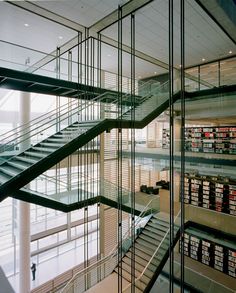 the inside of a building with glass stairs and bookshelves on each floor,