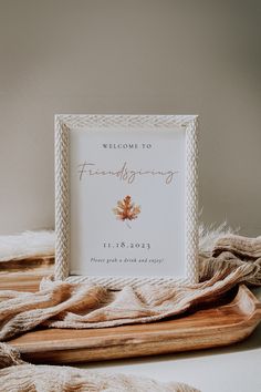 a welcome sign is placed on a wooden tray next to a blanket and throw pillows