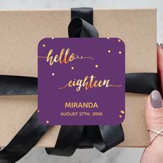 a gift wrapped in brown paper with black ribbon and gold foil lettering on the top