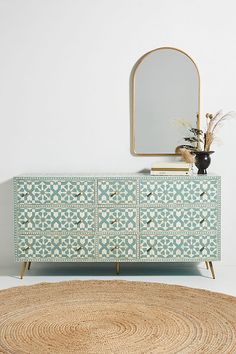 a white and blue dresser sitting next to a mirror