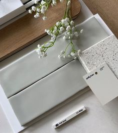 a vase with white flowers sitting on top of a counter next to a paint roller