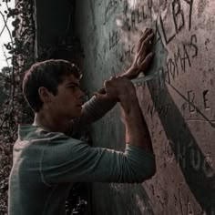 a young man writing on the side of a wall with his hands and fingers in front of him