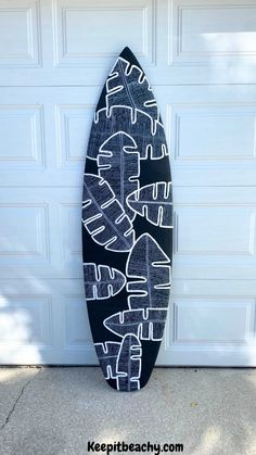 a black and white surfboard sitting in front of a garage door