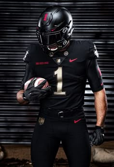 a football player wearing a black uniform and holding a ball