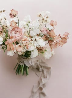 a bouquet of flowers sitting on top of a white table next to a pink wall