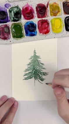 someone is drawing a christmas tree with watercolors