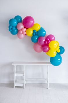 a bunch of balloons hanging from the side of a white wall next to a bench