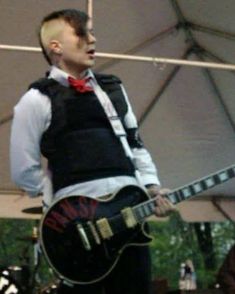 a man with a guitar standing under a tent