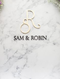 the logo for sam and robin on a marble wall with flowers in front of it