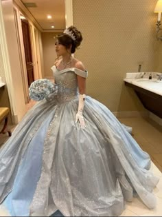 a woman in a blue and silver ball gown is looking at herself in the mirror