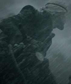 a man standing in the rain with his head down and an umbrella over his shoulder