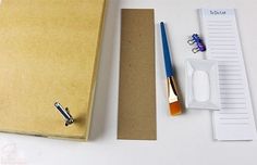 a binder, pen, and clipboard on a table with other office supplies