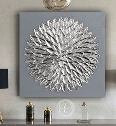 a large metal flower is mounted on the wall above a console table with two lamps