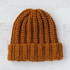 an orange knitted beanie sitting on top of a white wall