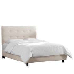 an upholstered bed with white sheets and pillows