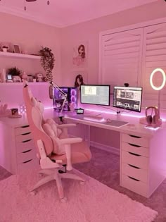 a pink room with two computer screens on the desk and a chair in front of it