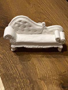 a white couch sitting on top of a wooden floor next to a knife and fork