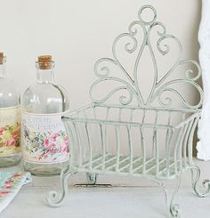 an iron basket with two bottles next to it on a counter top near a lace doily