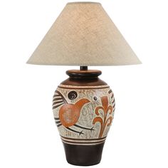 a lamp with a bird design on it and a beige shade over the top of the lamp