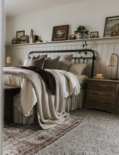 a bedroom with a bed, nightstands and pictures on the wall above it is shown