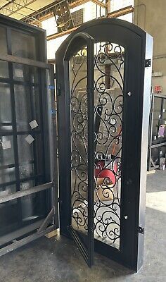 an ornate iron door with glass panels and metal bars on the sides, in a warehouse