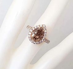 a brown and white diamond ring sitting on top of a white glove with it's fingers