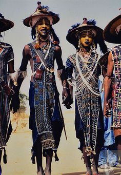 three men with painted faces and headdresses are walking in the desert together