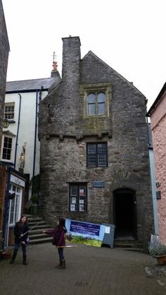 two people standing in front of an old stone building on a cobblestone street