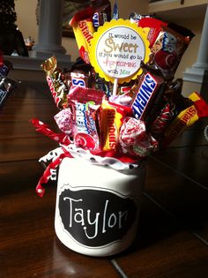 a cup filled with candy and candies on top of a wooden table next to a phone