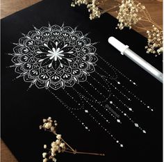 a black board with white designs on it next to some dried flowers and a pen