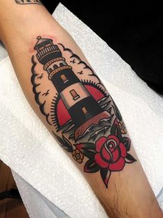 a man's arm with a lighthouse tattoo on it and roses in the background