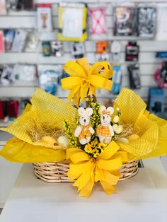 a basket filled with yellow bows and stuffed animals on top of a table next to a wall