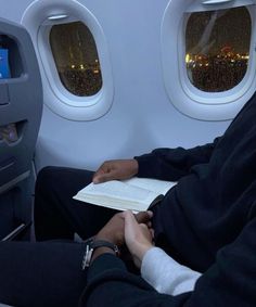 a person sitting on an airplane reading a book