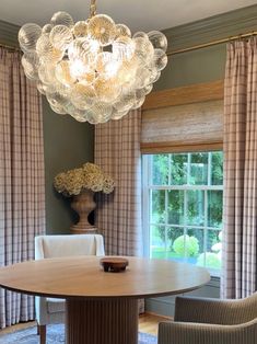 a dining room table with chairs and a chandelier hanging from it's ceiling