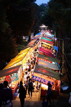 many tents are set up on the side of a road at night with people walking around them