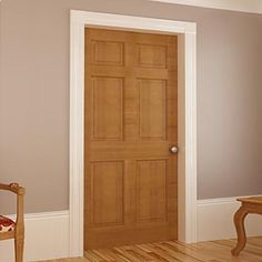 an empty room with a wooden door and chair