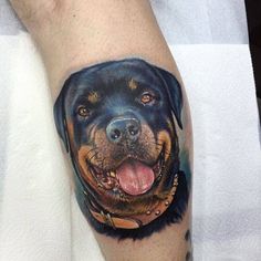 a man's arm with a tattoo of a rotter dog on it and his tongue hanging out