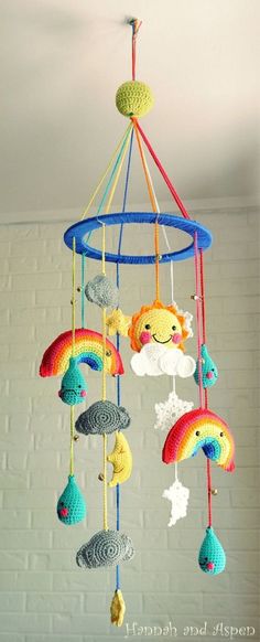 a crocheted mobile hanging from the ceiling with rainbows and clouds on it