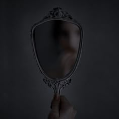 a person holding a mirror in front of their face with the reflection of them on it