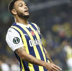 a soccer player looking up at the sky with his hand on his hip while wearing a yellow and blue striped shirt