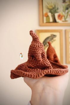 a hand holding up a knitted hat with two small crochets on it